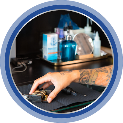 Image of someone reaching for a tattoo machine